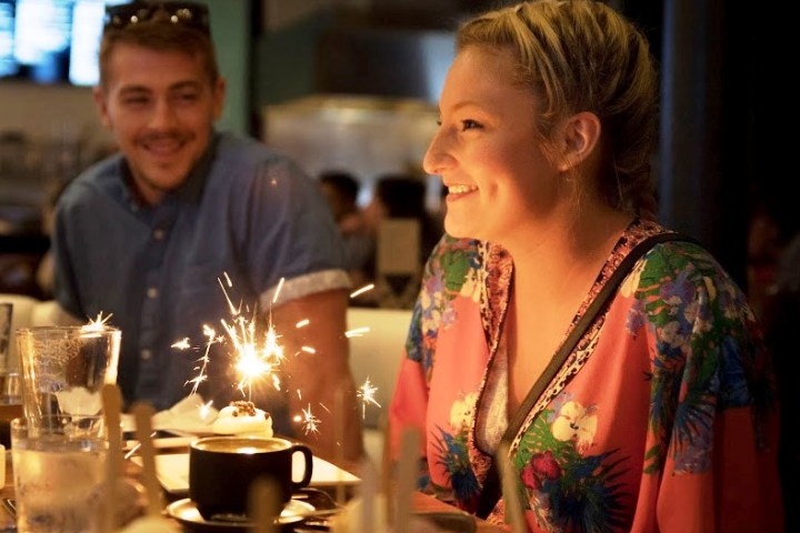 a person standing in front of a birthday cake with lit candles